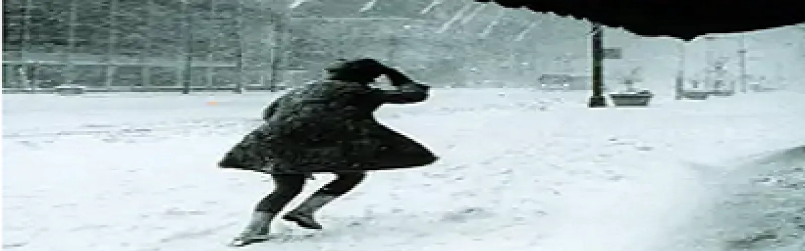 woman walking against wind in snowstorm